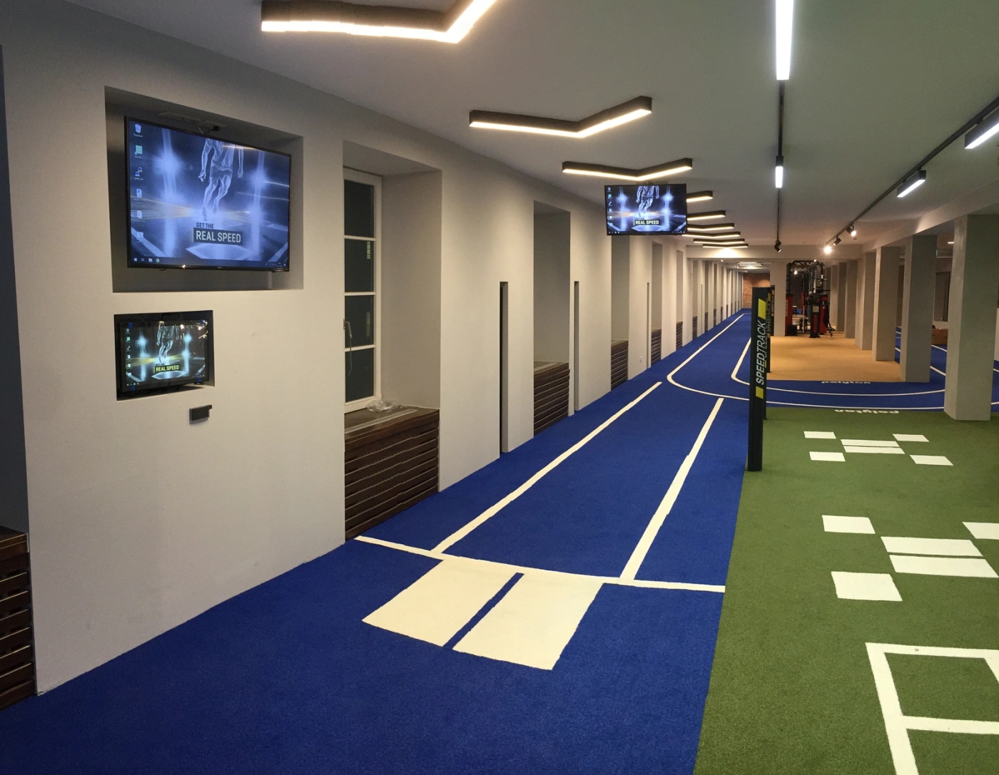 Синяя дорожка SpeedTrack с белыми стартовыми пластинами и экранами в клубном зале