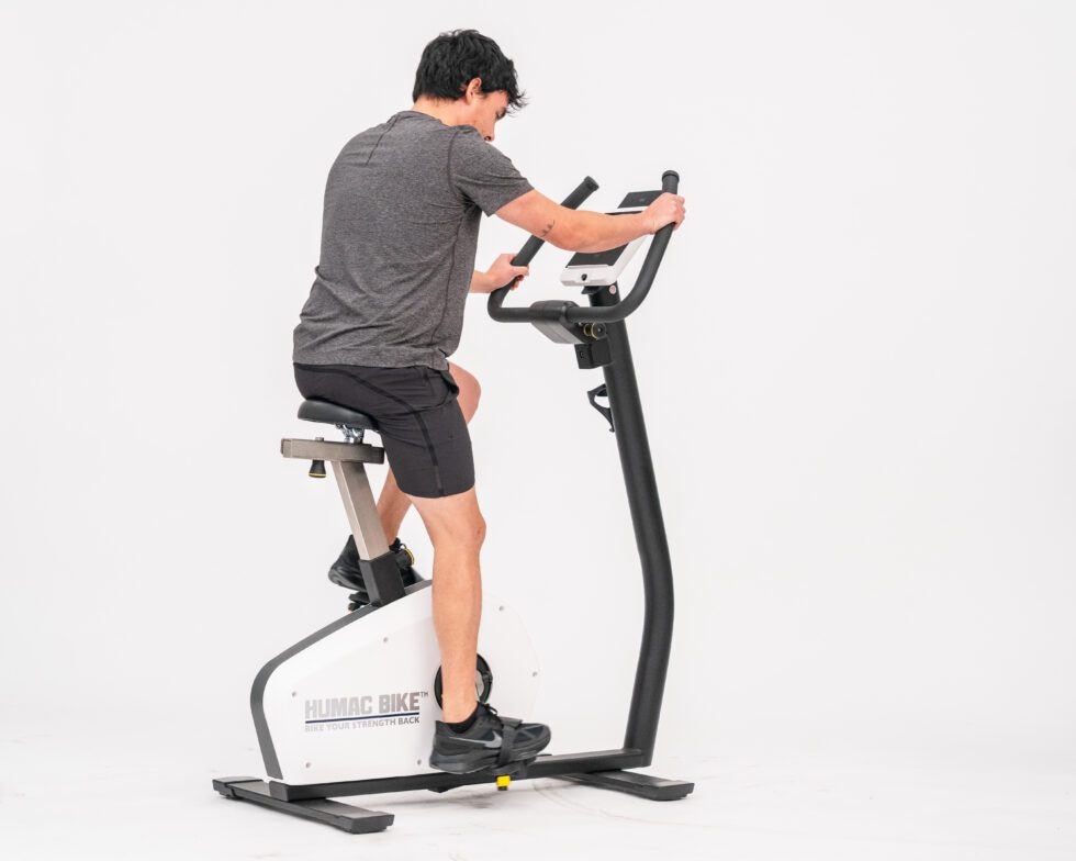 Мужчина крутит педали велотренажёра HUMAC BIKE, вид сбоку