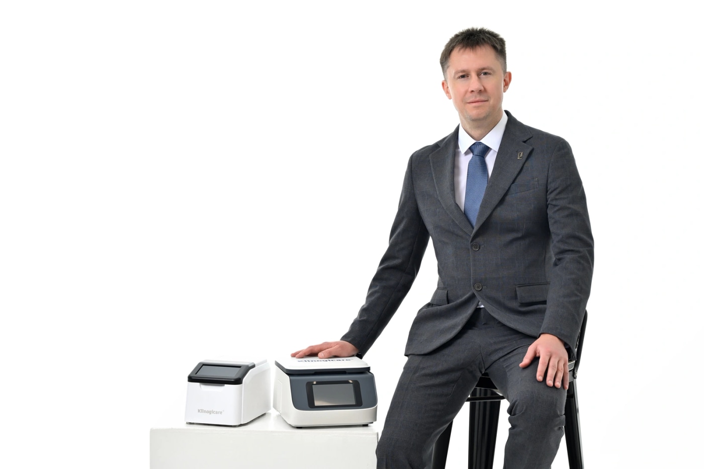 Два анализатора Klinogicare StarLab, Biochem и Hormones & Proteins, на белом подиуме рядом со специалистом