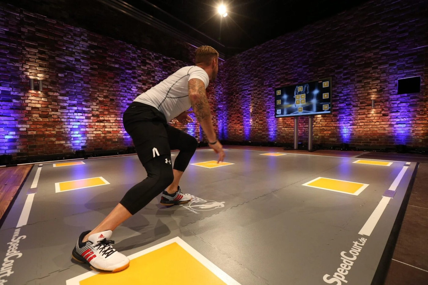 Спортсмен разгоняется по площадке SpeedCourt с жёлтыми сенсорными зонами перед экраном