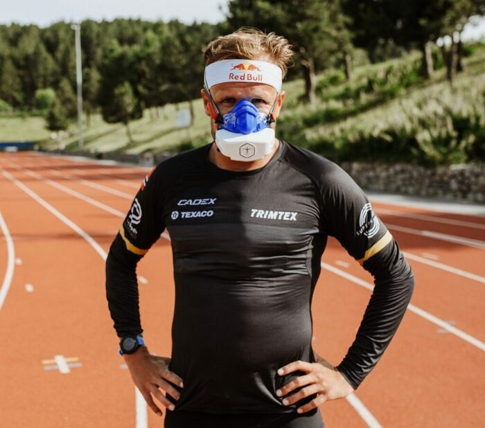 Спортсмен в анализаторе VO2 Master стоит на беговой дорожке стадиона
